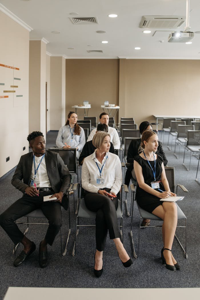 about-us Group of professionals attentively sitting in a modern conference room setting.