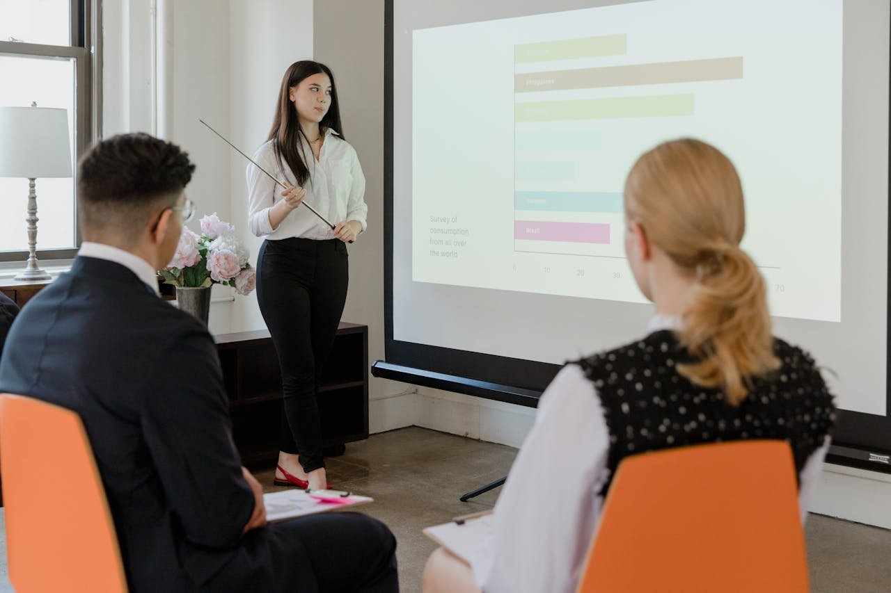services-01 A young professional presenting data in a modern office to attentive colleagues.